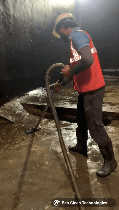 Worker using suction machine in tank