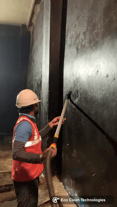 Worker jet washing tank wall