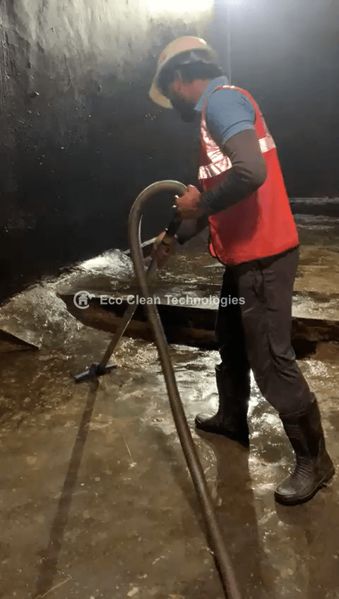 Worker using suction machine in tank